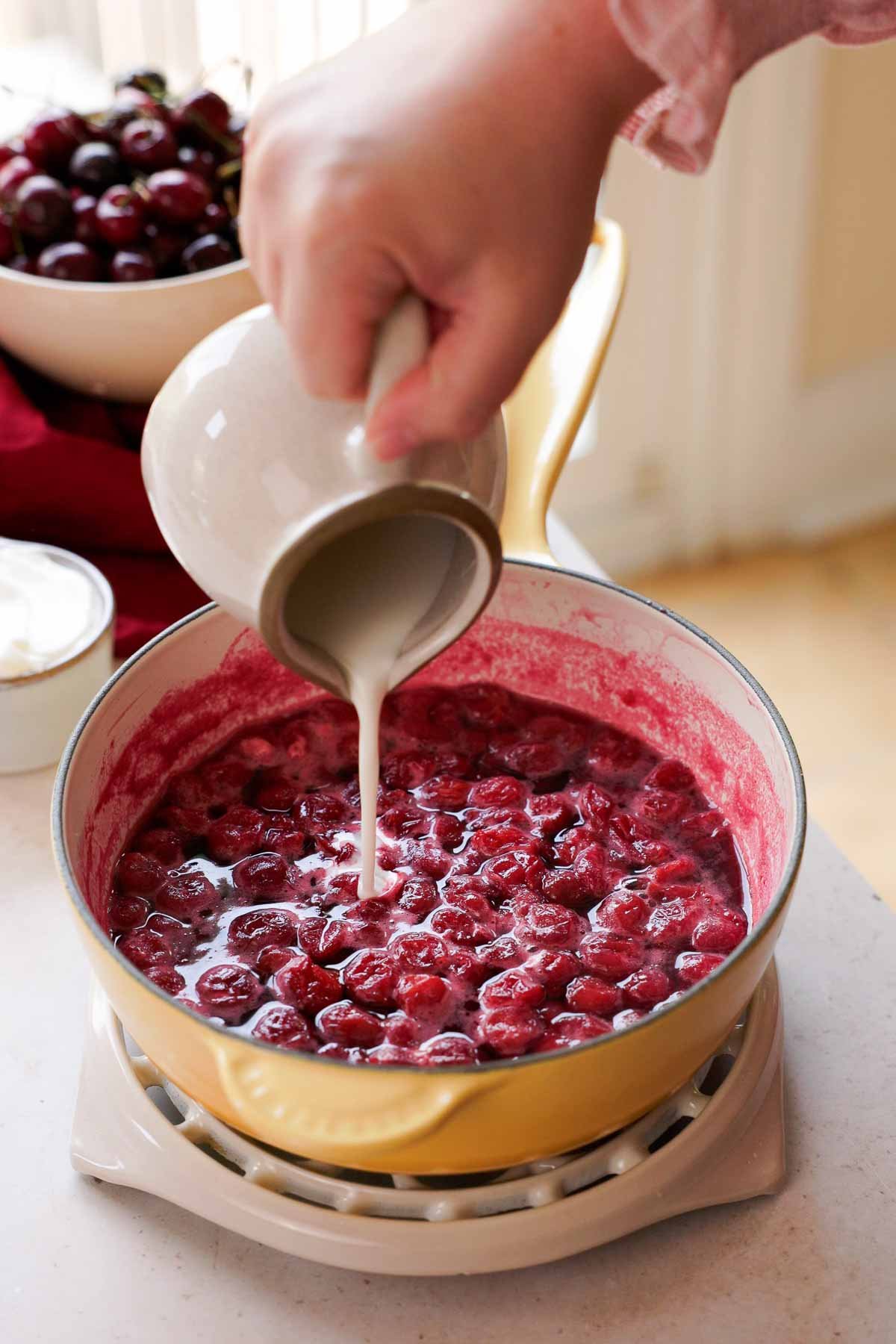 pouring cornstarch slurry into simmering cherries