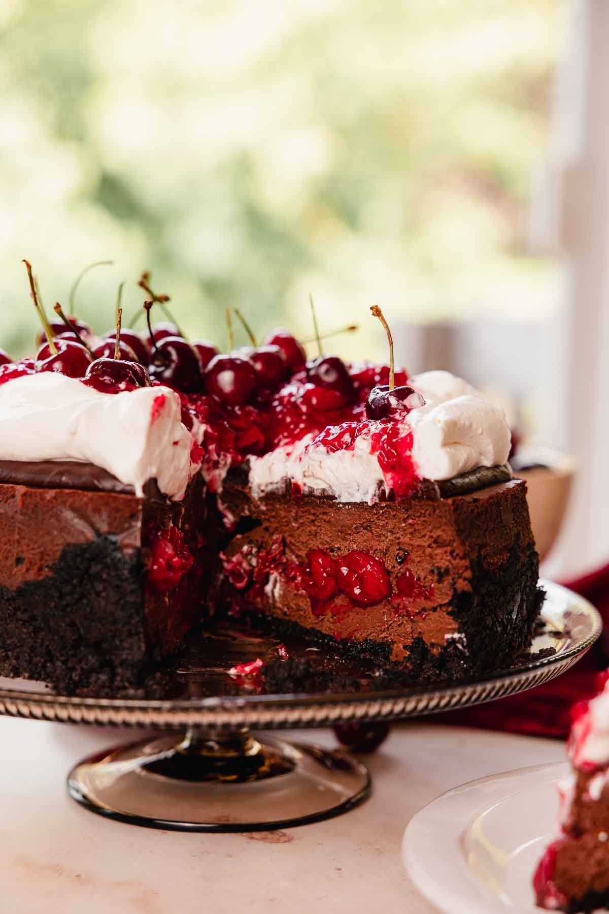 black forest cheesecake with cherry filling, whipped cream, chocolate ganache, and cherries