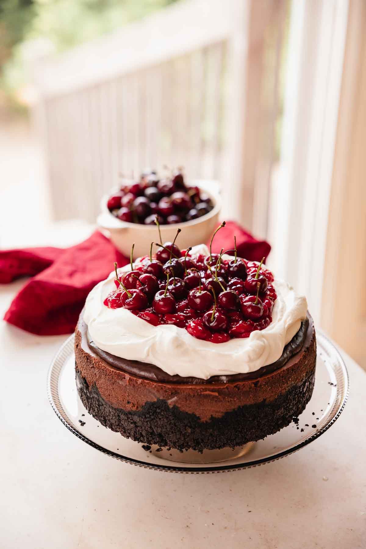 black forest cheesecake with cherry center, chocolate ganache, whipped cream, and fresh cherries on top