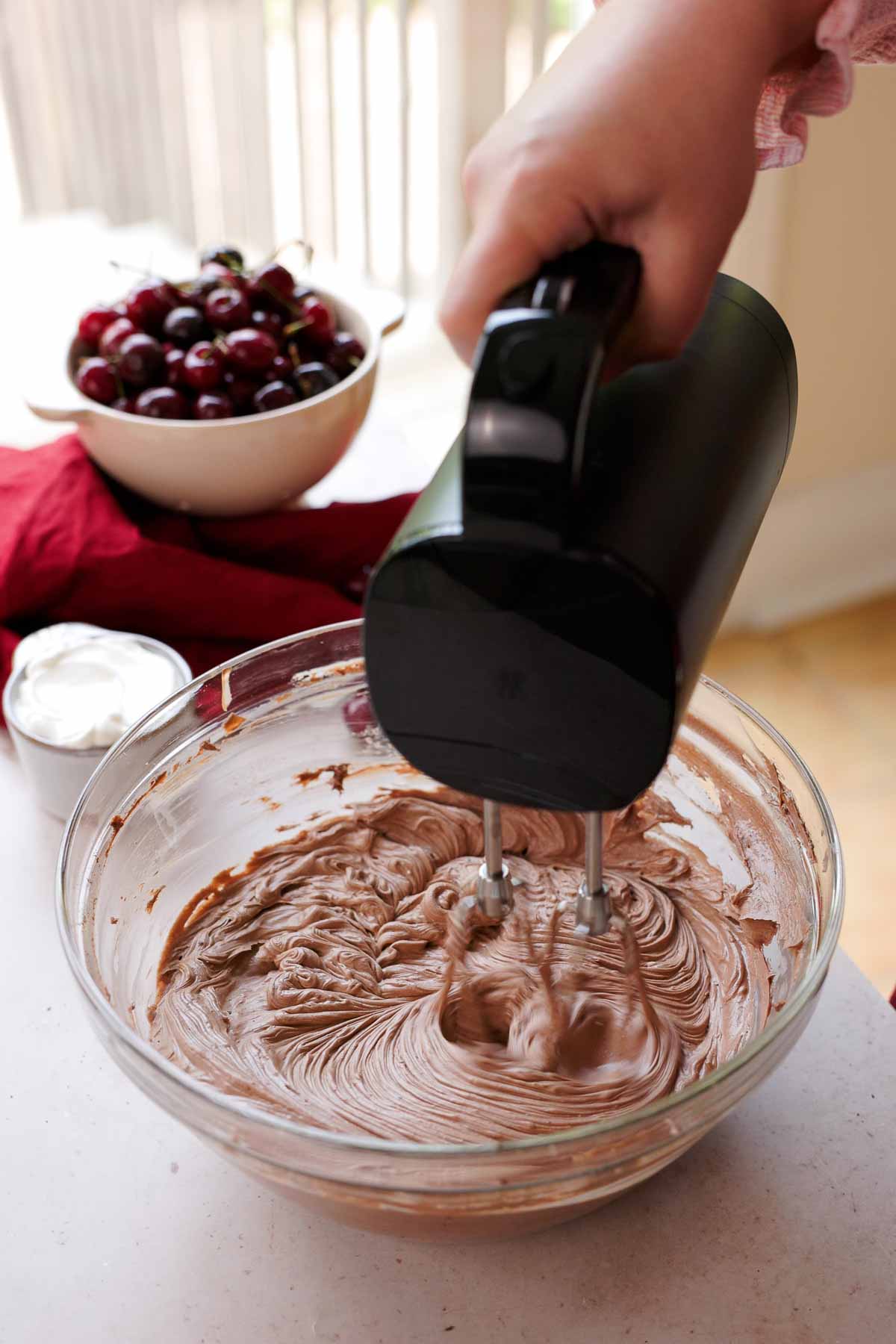 mixing cream cheese, sugar, and cocoa powder with electric mixer in large glass bowl