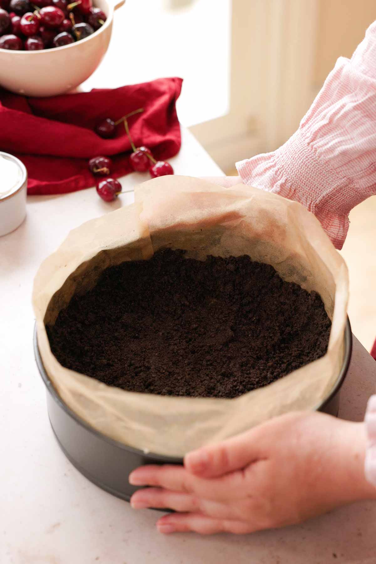 oreo crust in springform pan with parchment paper ring