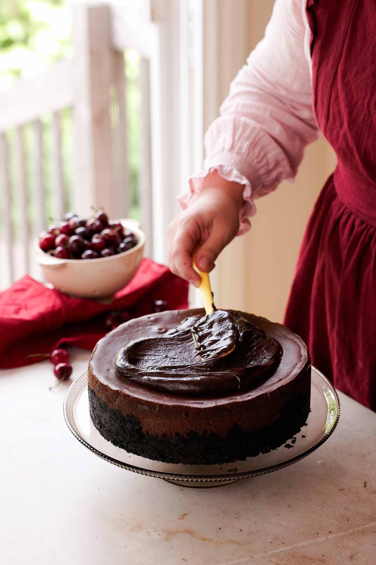 smoothing chocolate ganache onto black forest cheesecake