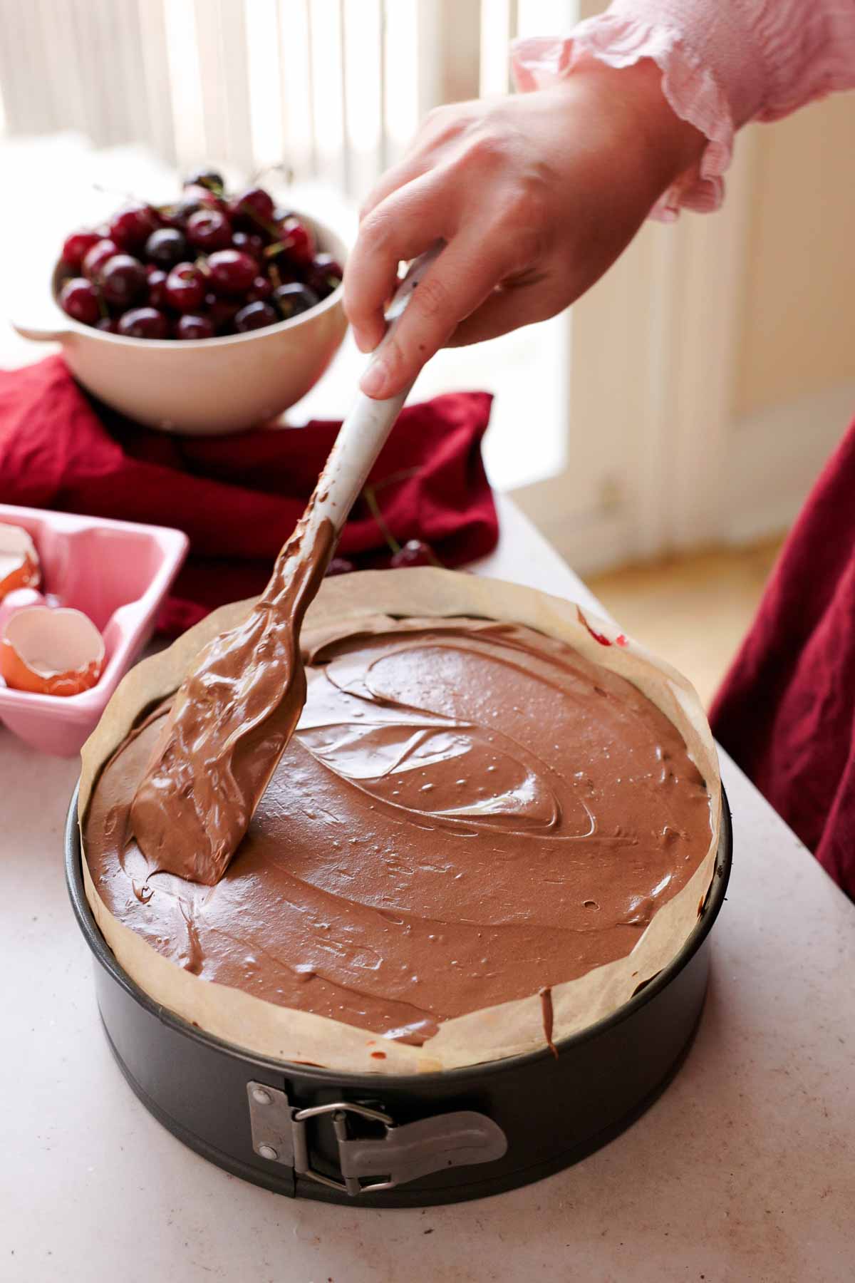 smoothing the top of chocolate cherry cheesecake with a spatula