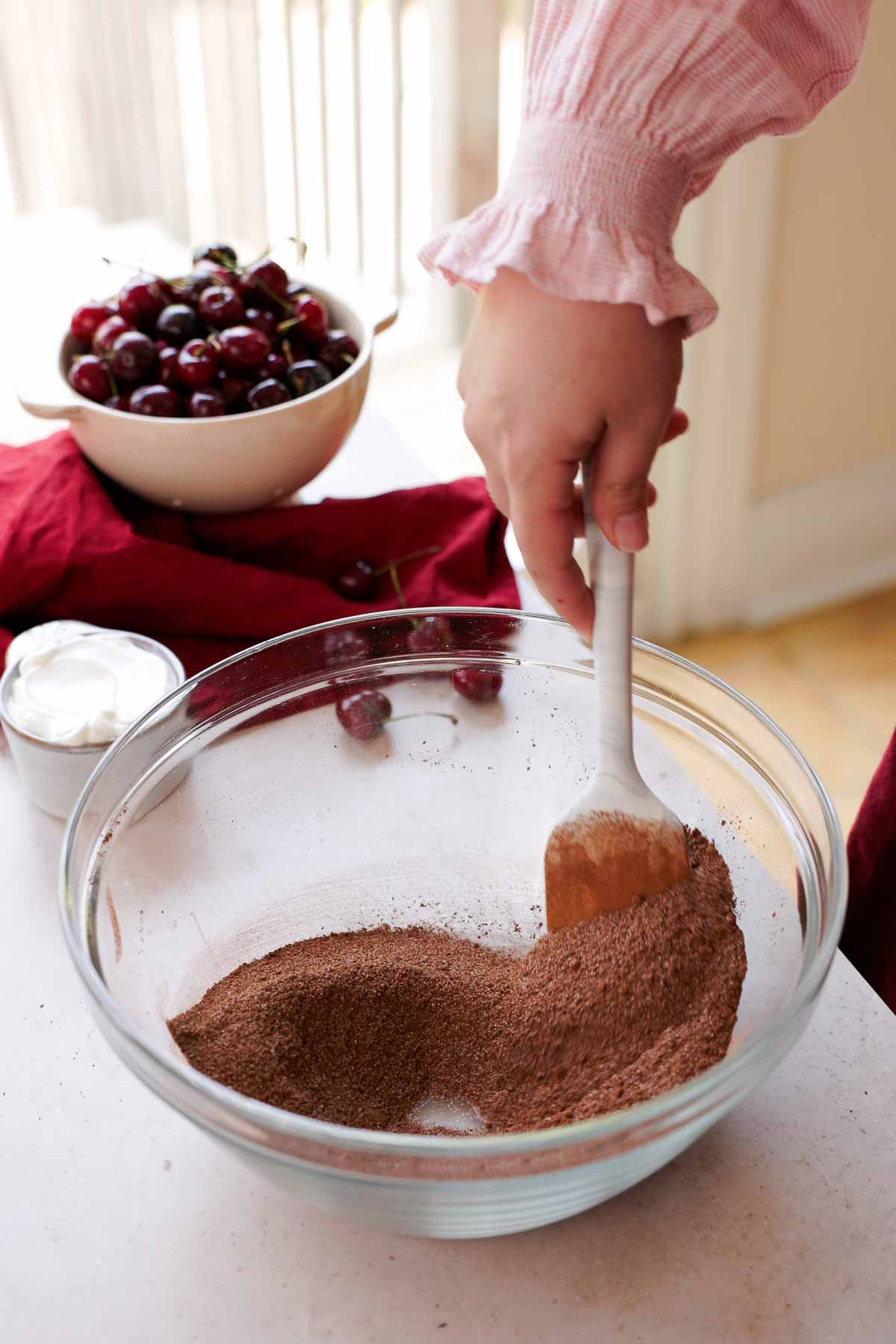 stirring sugar and cocoa powder in large glass bowl with spatula