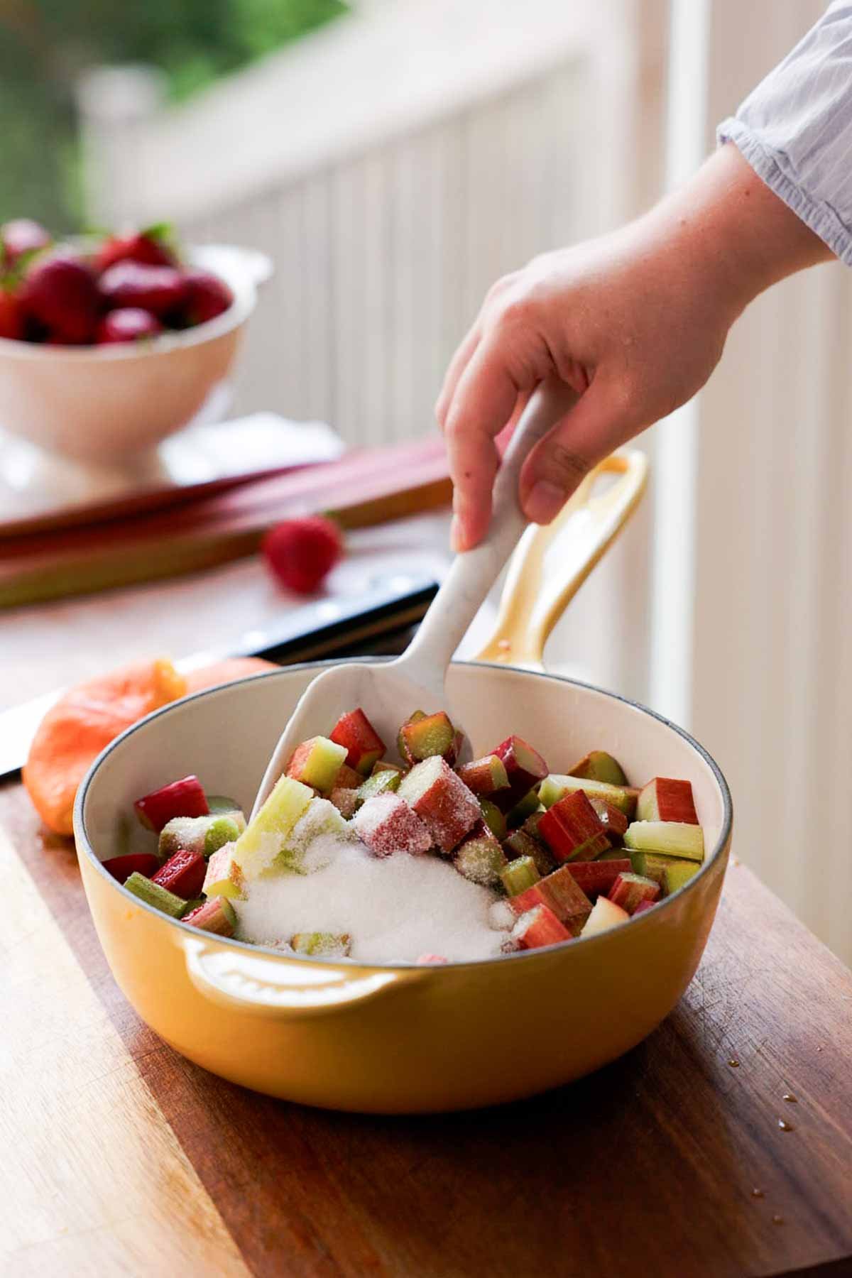 stirring rhubarb chunks and sugar together in saucepan