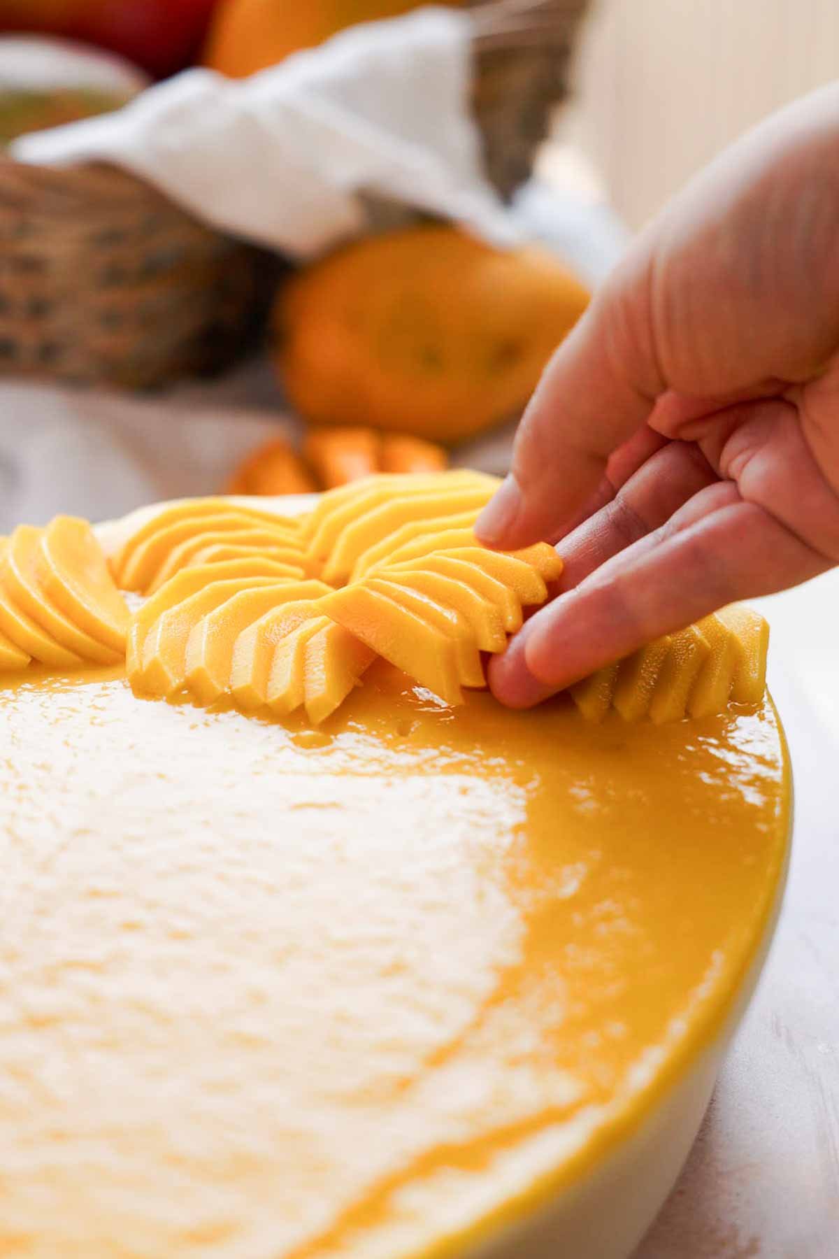 laying sliced fresh mango on tiramisu