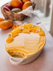 mango tiramisu in white tray with mango curd and fresh mango slices