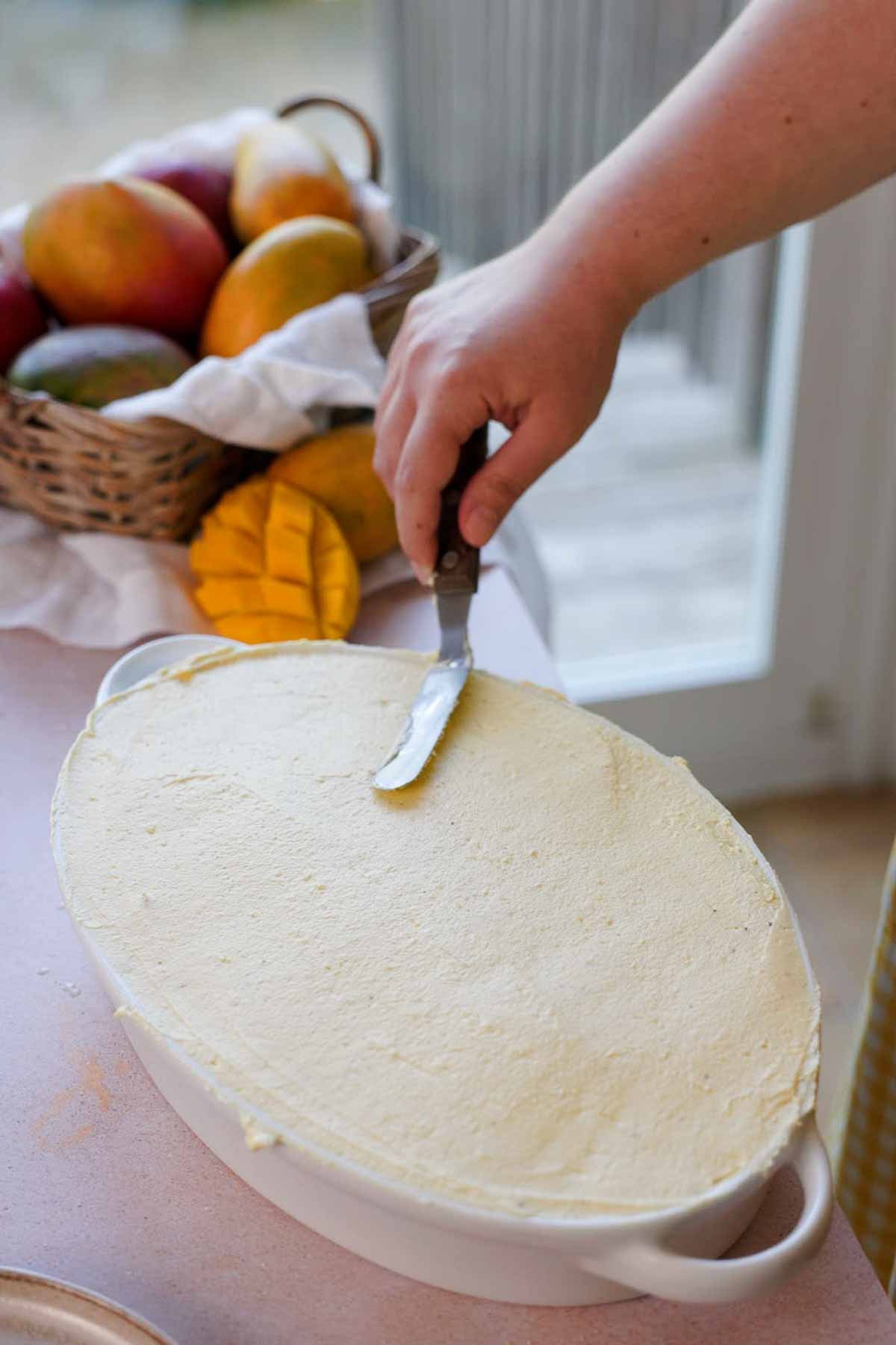 smoothing the top of mango tiramisu with spatula