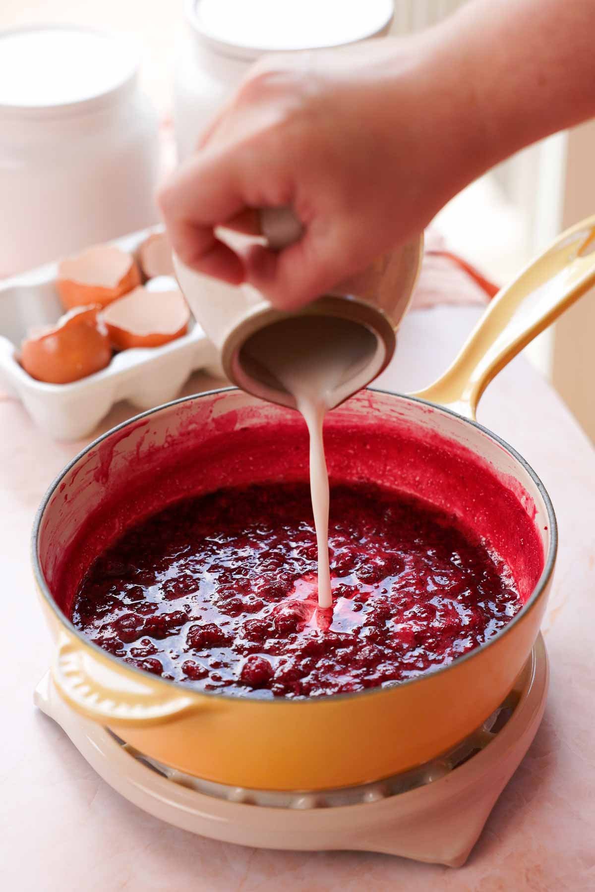 pouring cornstarch slurry into raspberry sauce