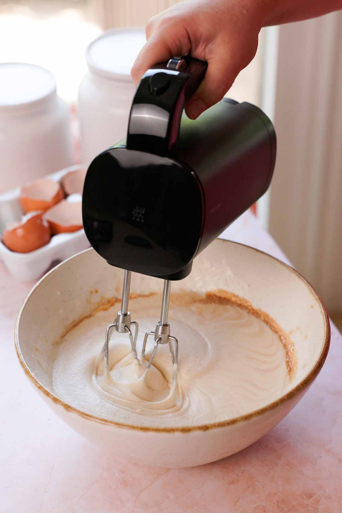 beating coconut batter wet ingredients with mixer in bowl