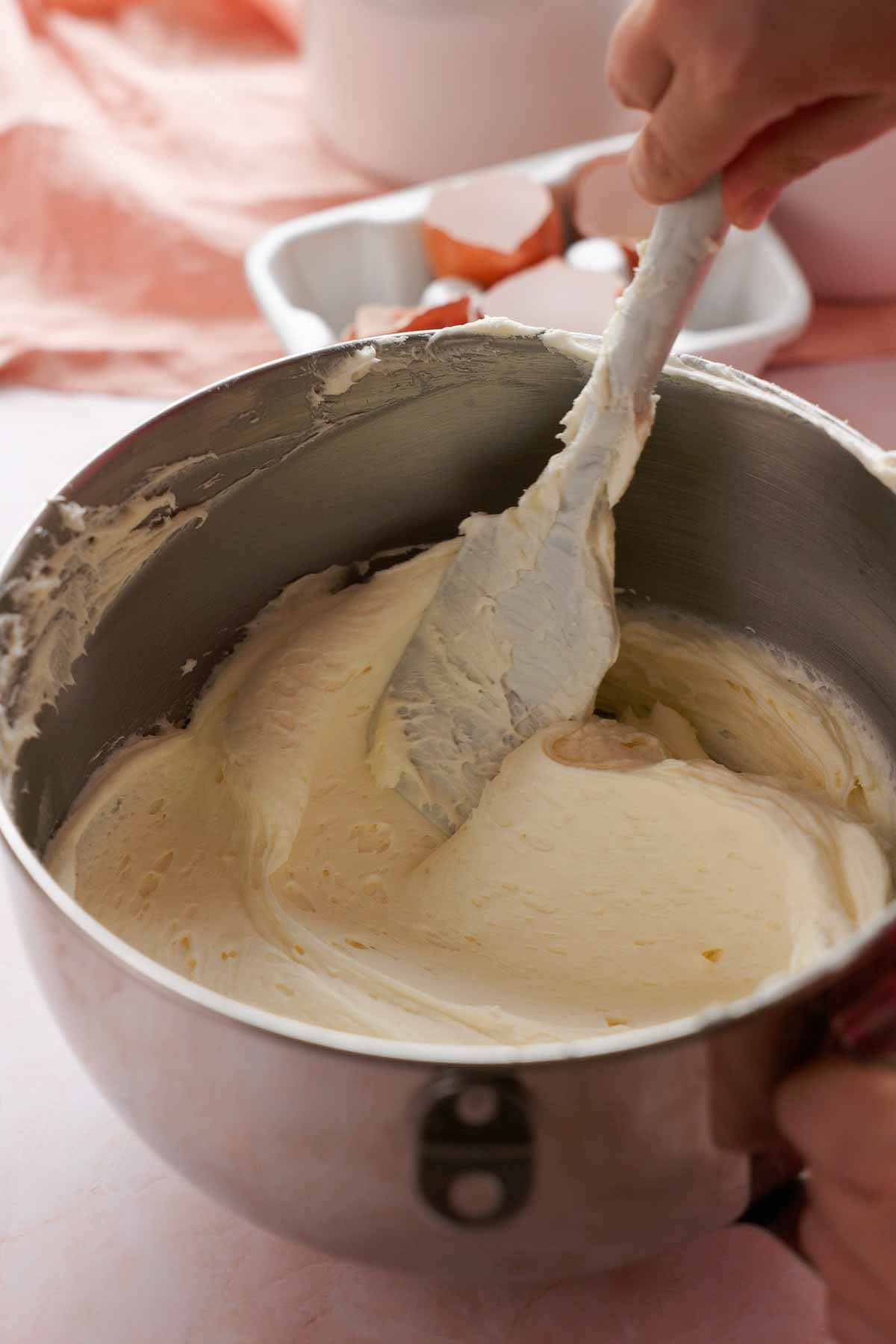 running a spatula through coconut cream cheese frosting in large mixing bowl