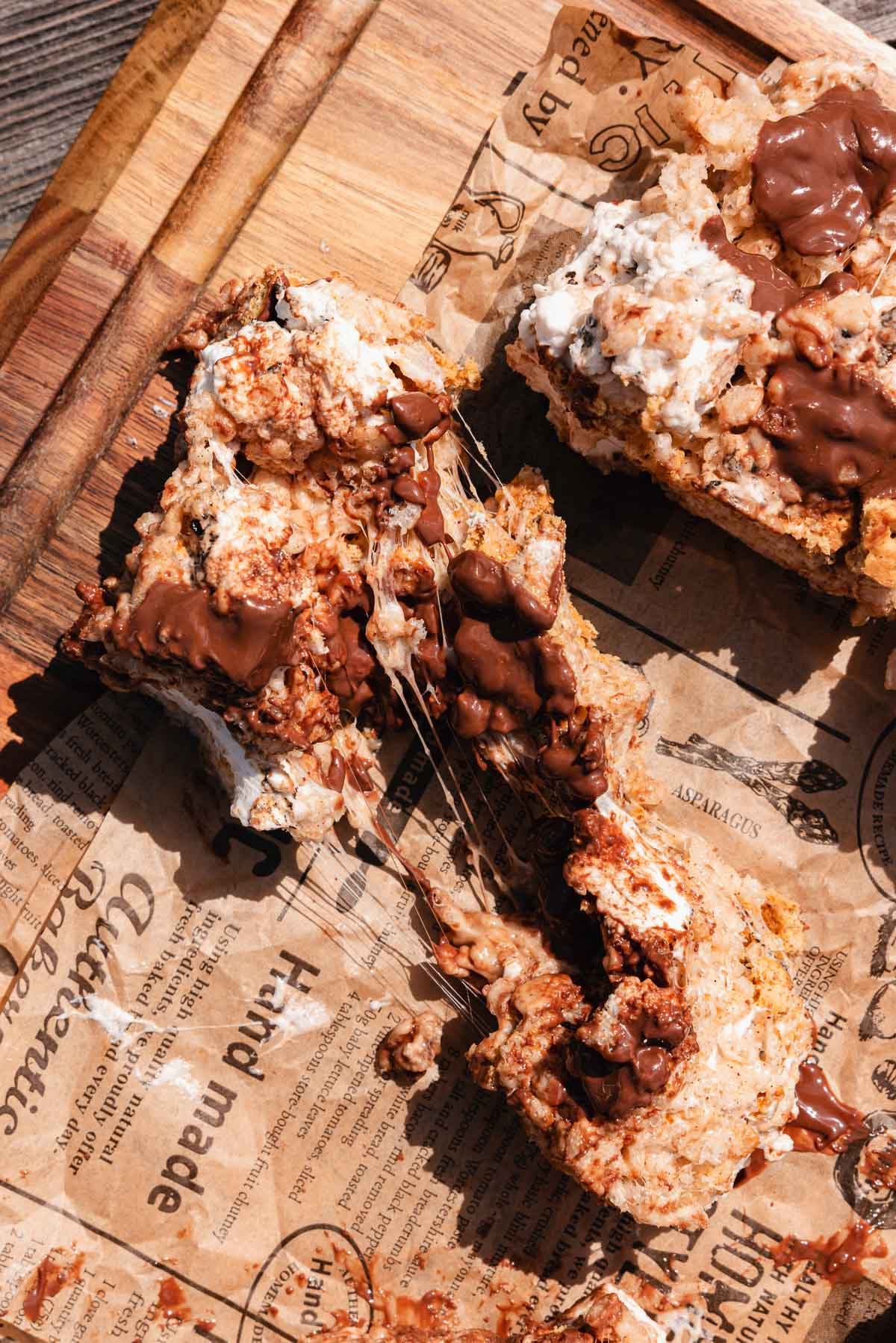 one piece of smores rice krispies treat on piece of parchment paper with ooey gooey marshmallow pull