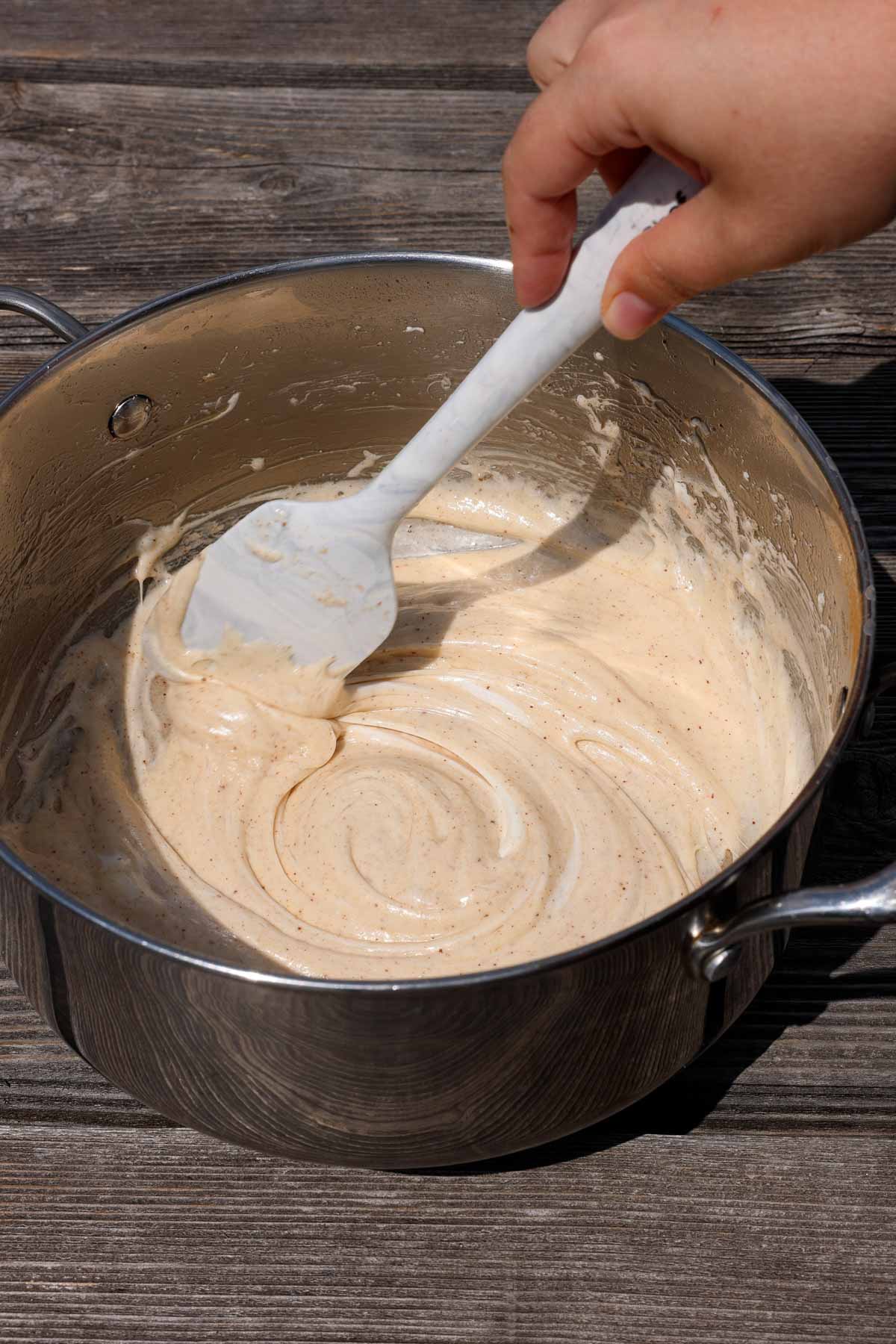 melting marshmallows and brown butter in a pot, stirring with a silicone spatula