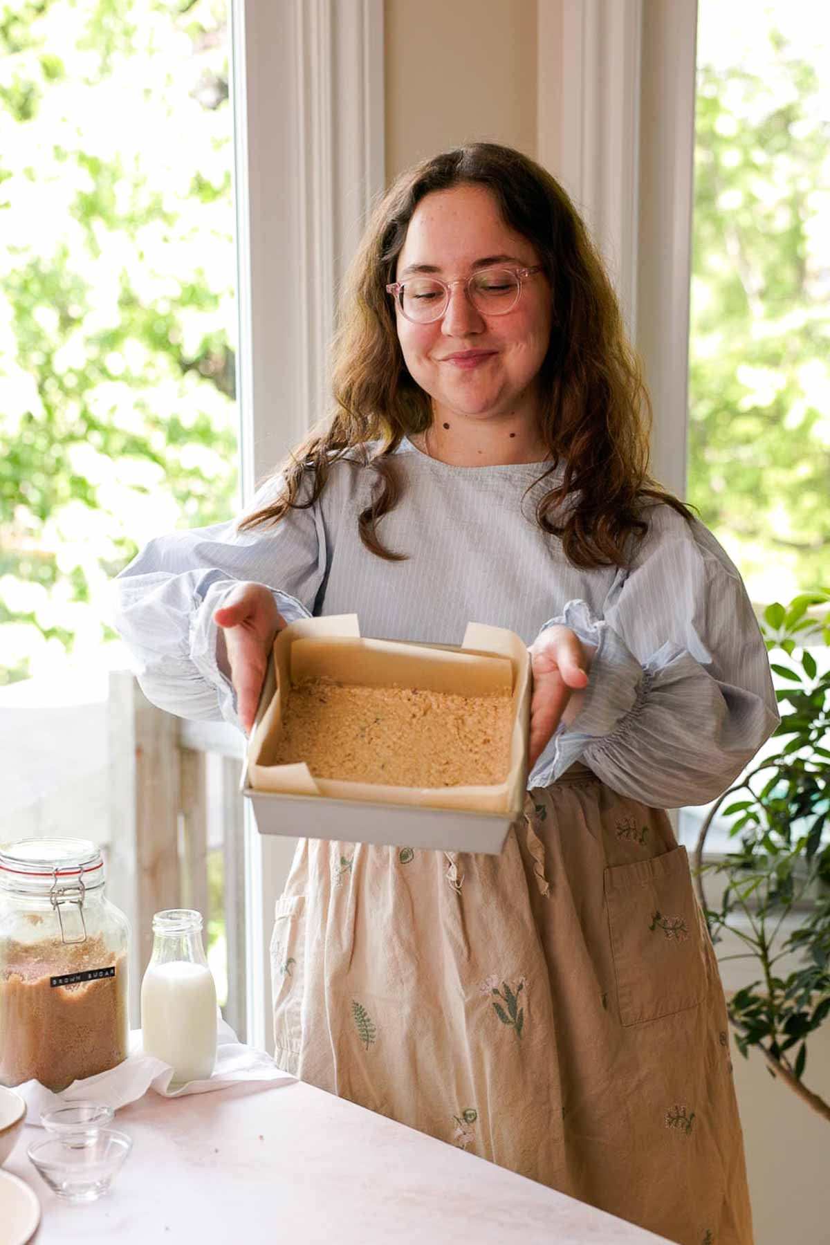 holding spread out oatmeal cookie dough in baking pan