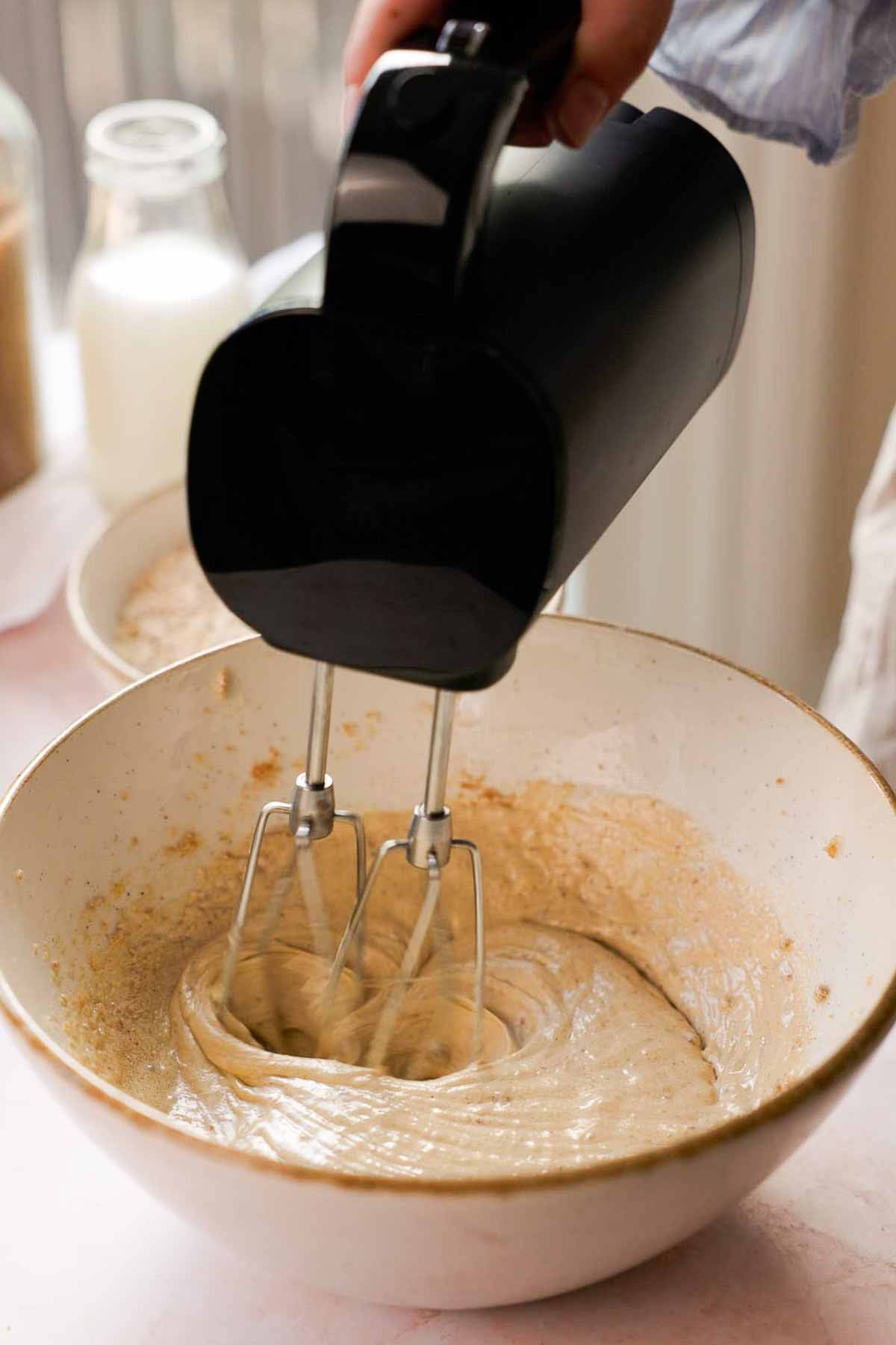 mixing oatmeal ice cream sandwich cookie wet ingredients in a bowl with an electric mixer