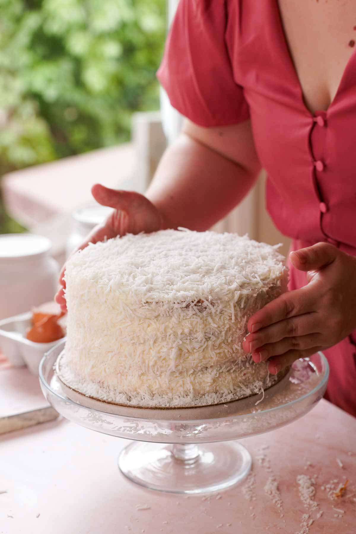 pressing shredded coconut onto frosted coconut cake
