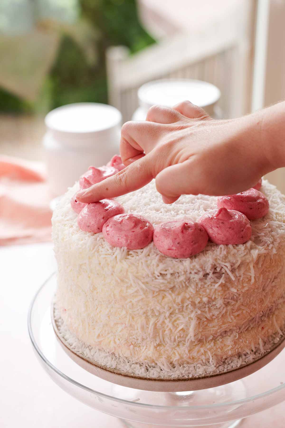 patting raspberry frosting peaks with fingers