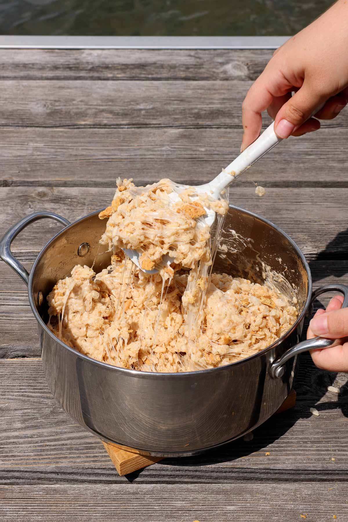 stirring melted marshmallows, rice krispies, and graham crackers in a pot