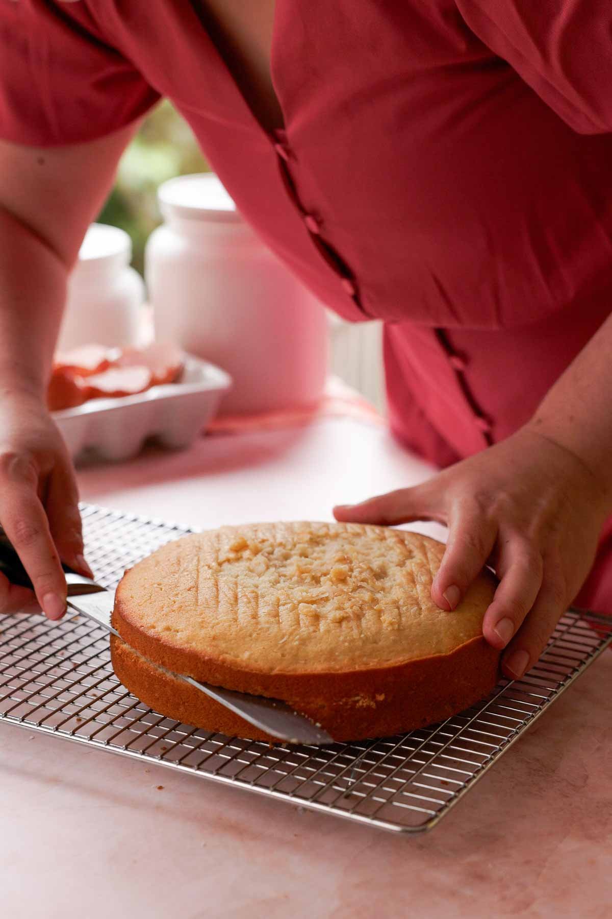 slicing coconut cake layer in half to create two coconut cake layers