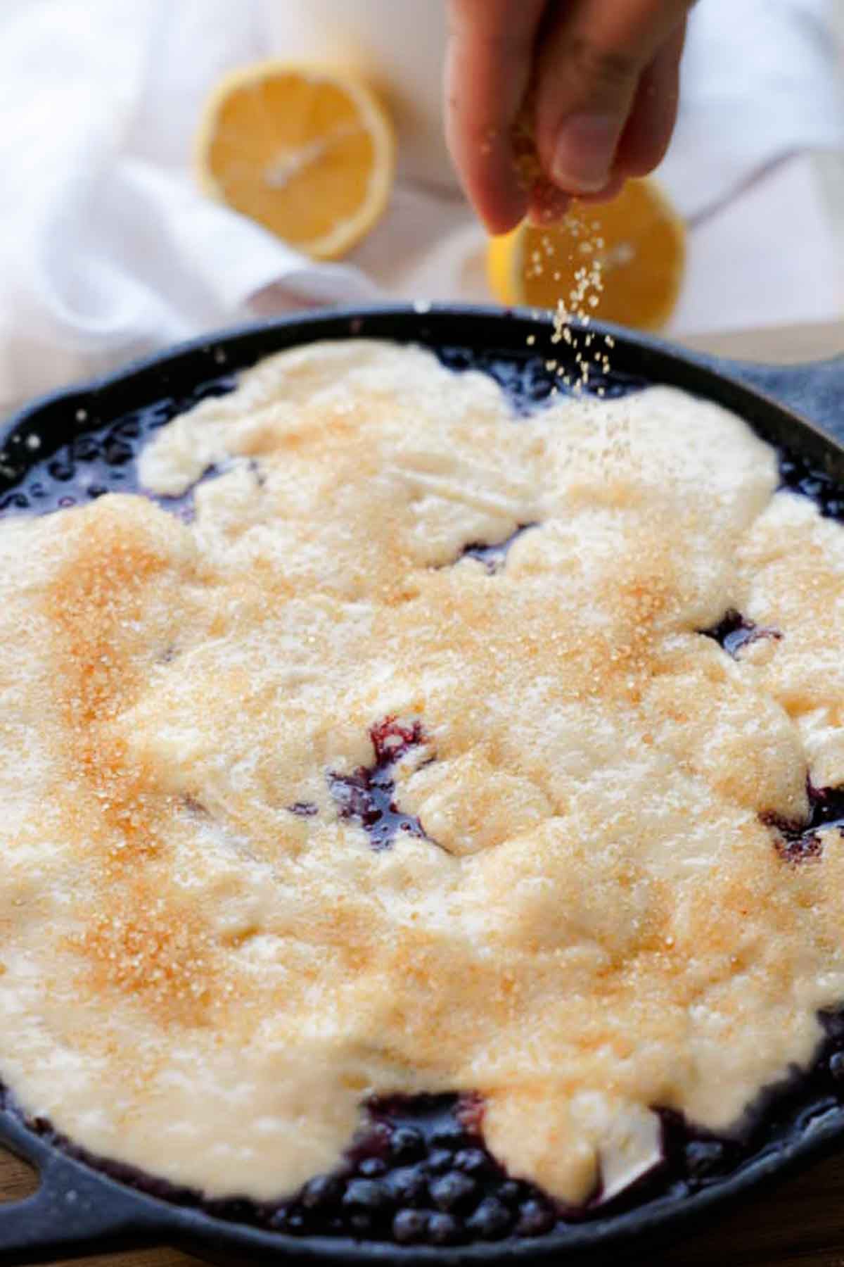 sprinkling demerara sugar onto blueberry cobbler