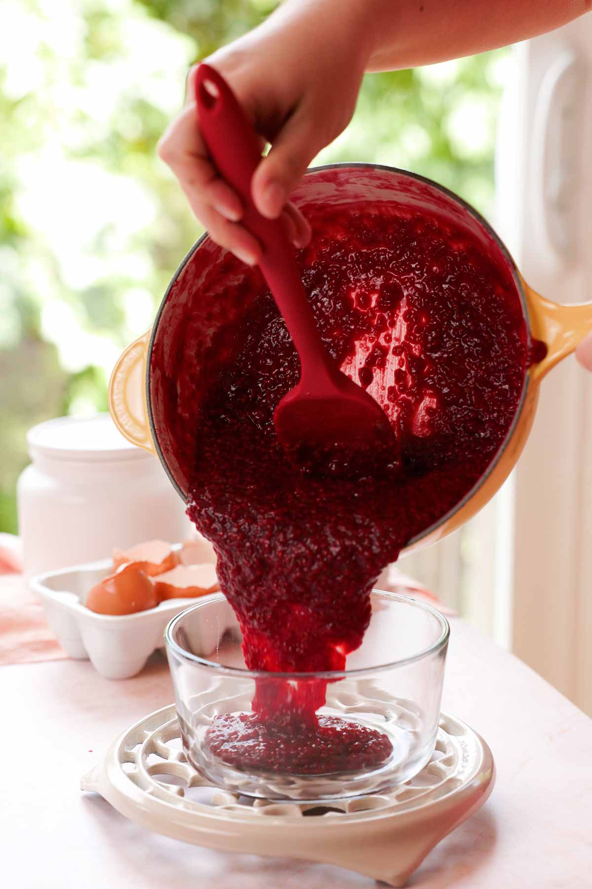 transferring raspberry cake filling into a glass container