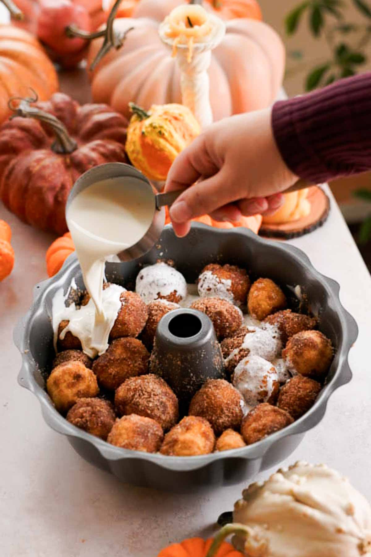 pouring cream over pumpkin monkey bread in bundt pan