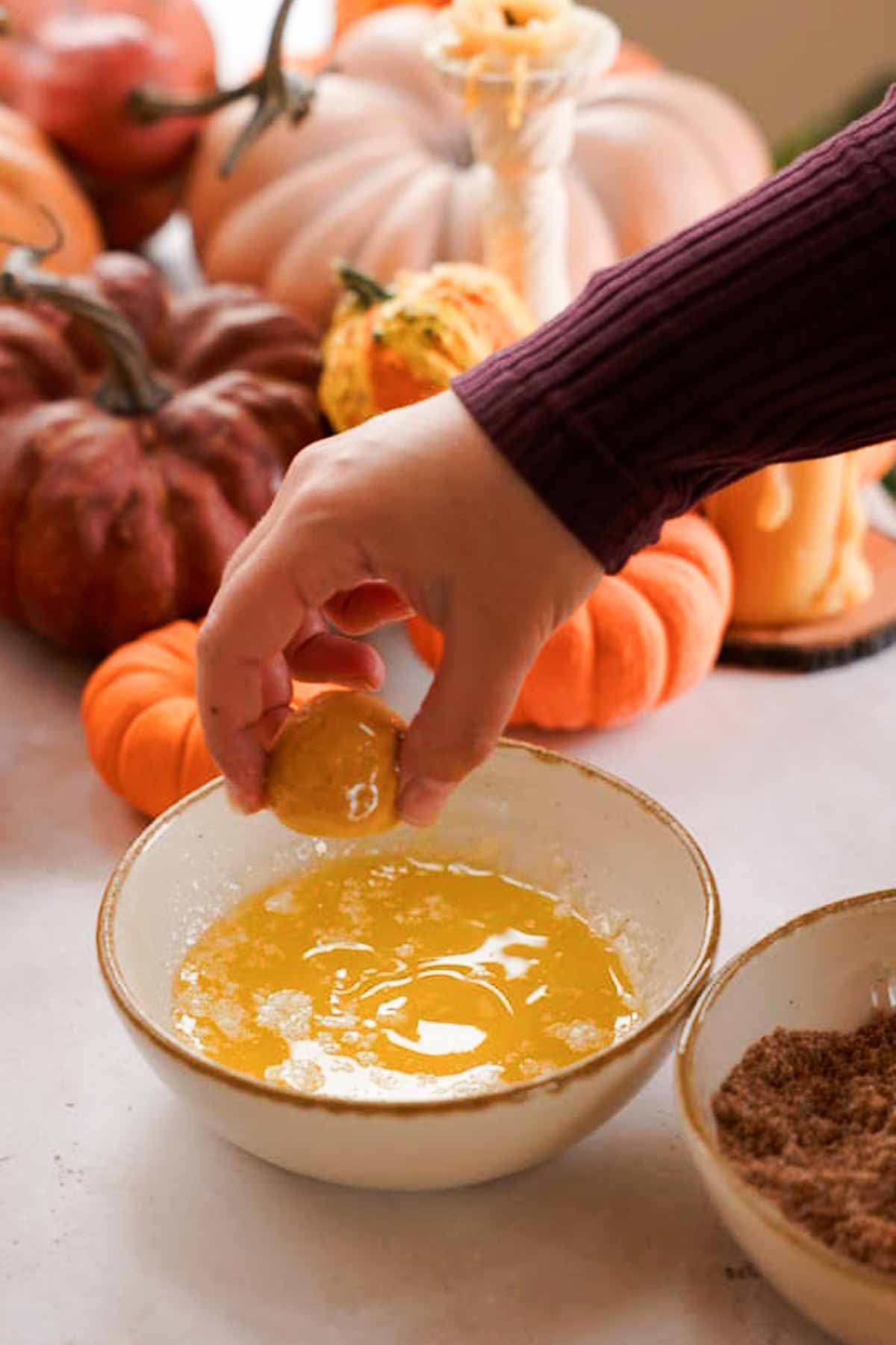 coating pumpkin monkey bread balls in melted butter