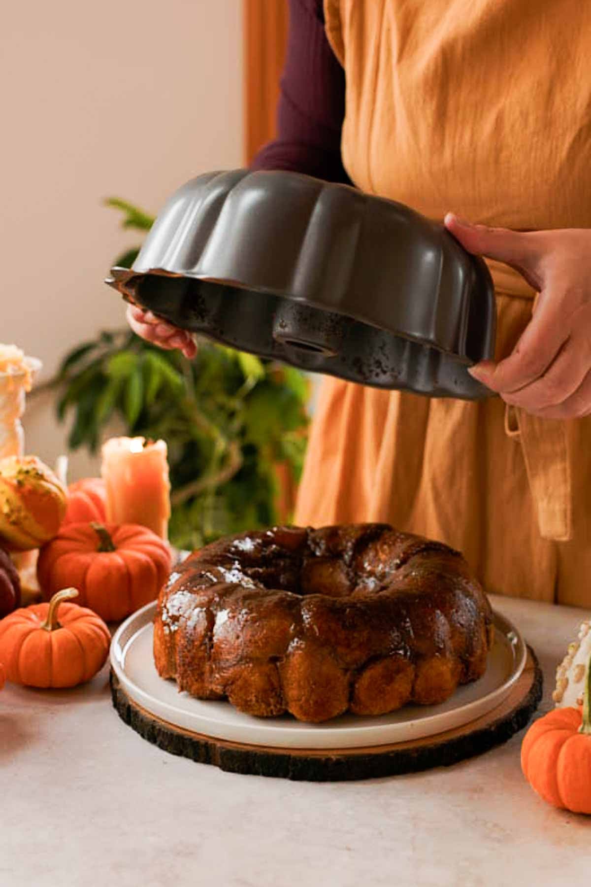 lifting bundt pan off pumpkin monkey bread stuffed with cream cheese