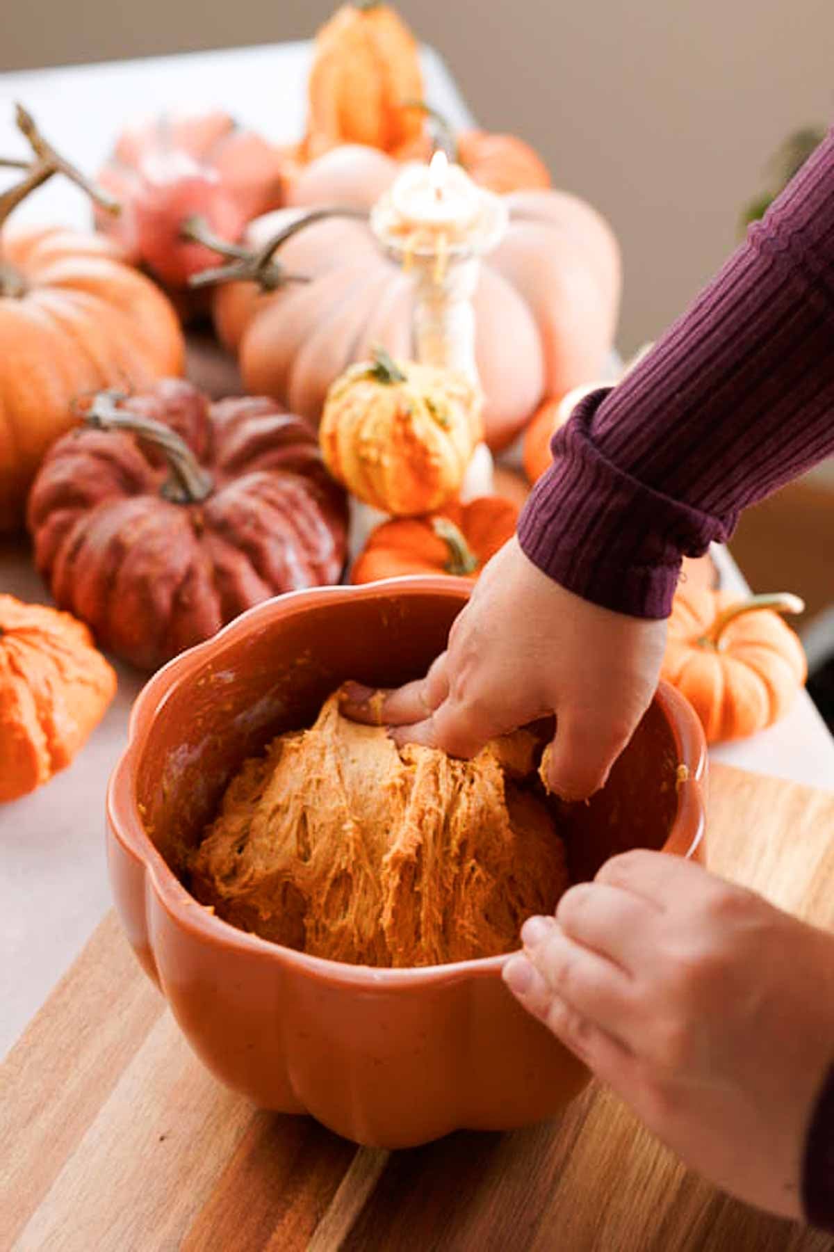 folding risen pumpkin dough in bowl