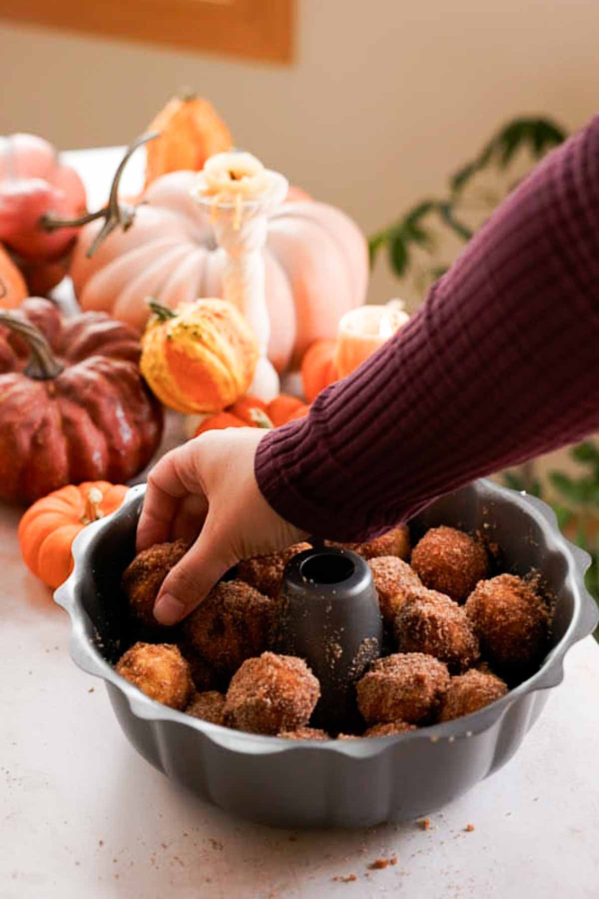 placing pumpkin monkey bread dough balls into bundt pan