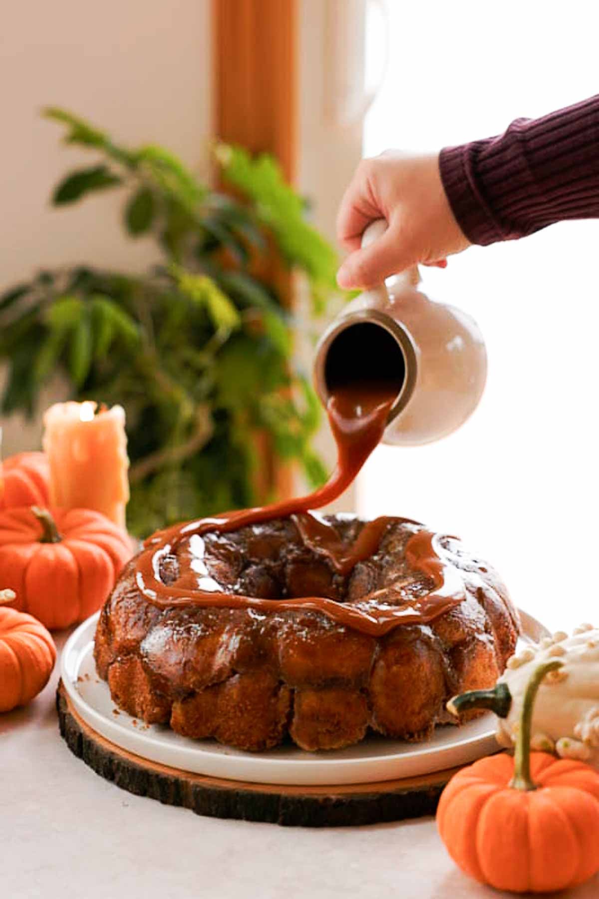 pouring caramel sauce over pumpkin monkey bread