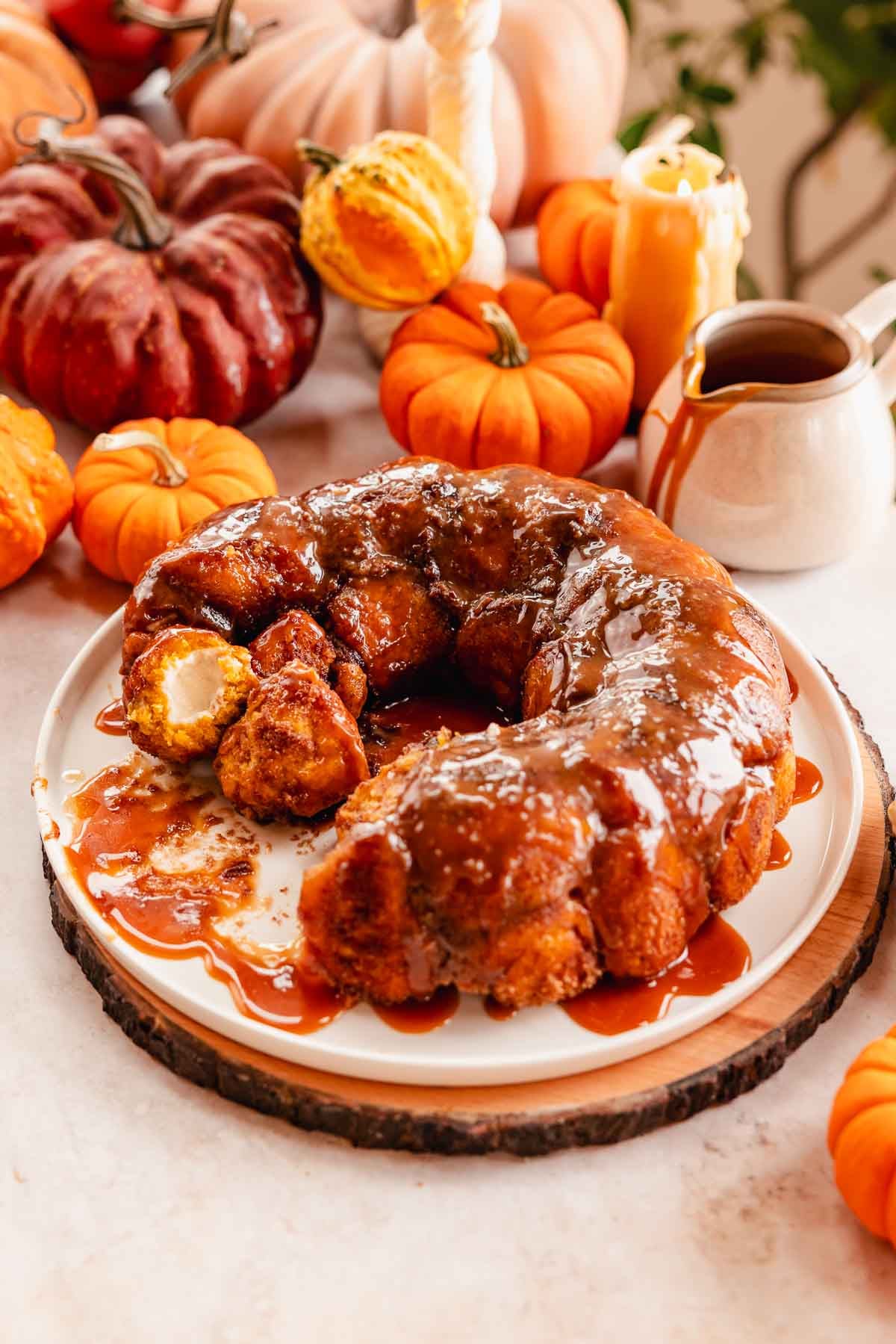 pumpkin monkey bread stuffed with cream cheese filling on a large plate with caramel sauce