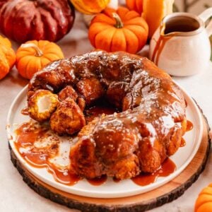 pumpkin monkey bread stuffed with cream cheese filling on a large plate with caramel sauce