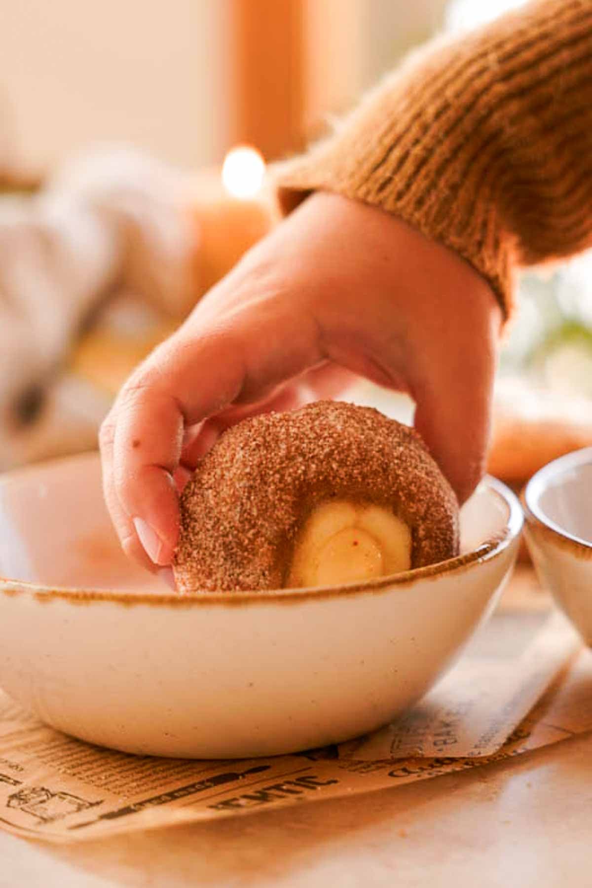 rolling apple cider muffin into cinnamon sugar