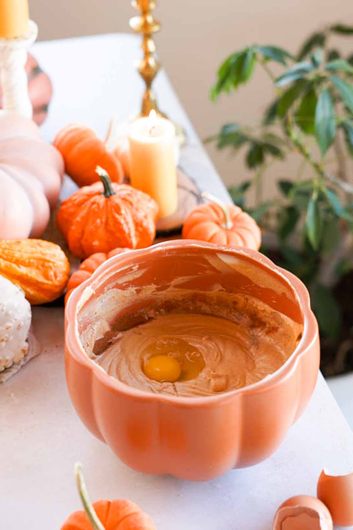 adding eggs into pumpkin cheesecake batter in a bowl