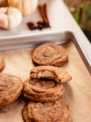 chai cookies on baking tray with one bitten to show cheesecake filling