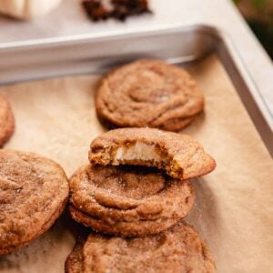 chai cookies on baking tray with one bitten to show cheesecake filling