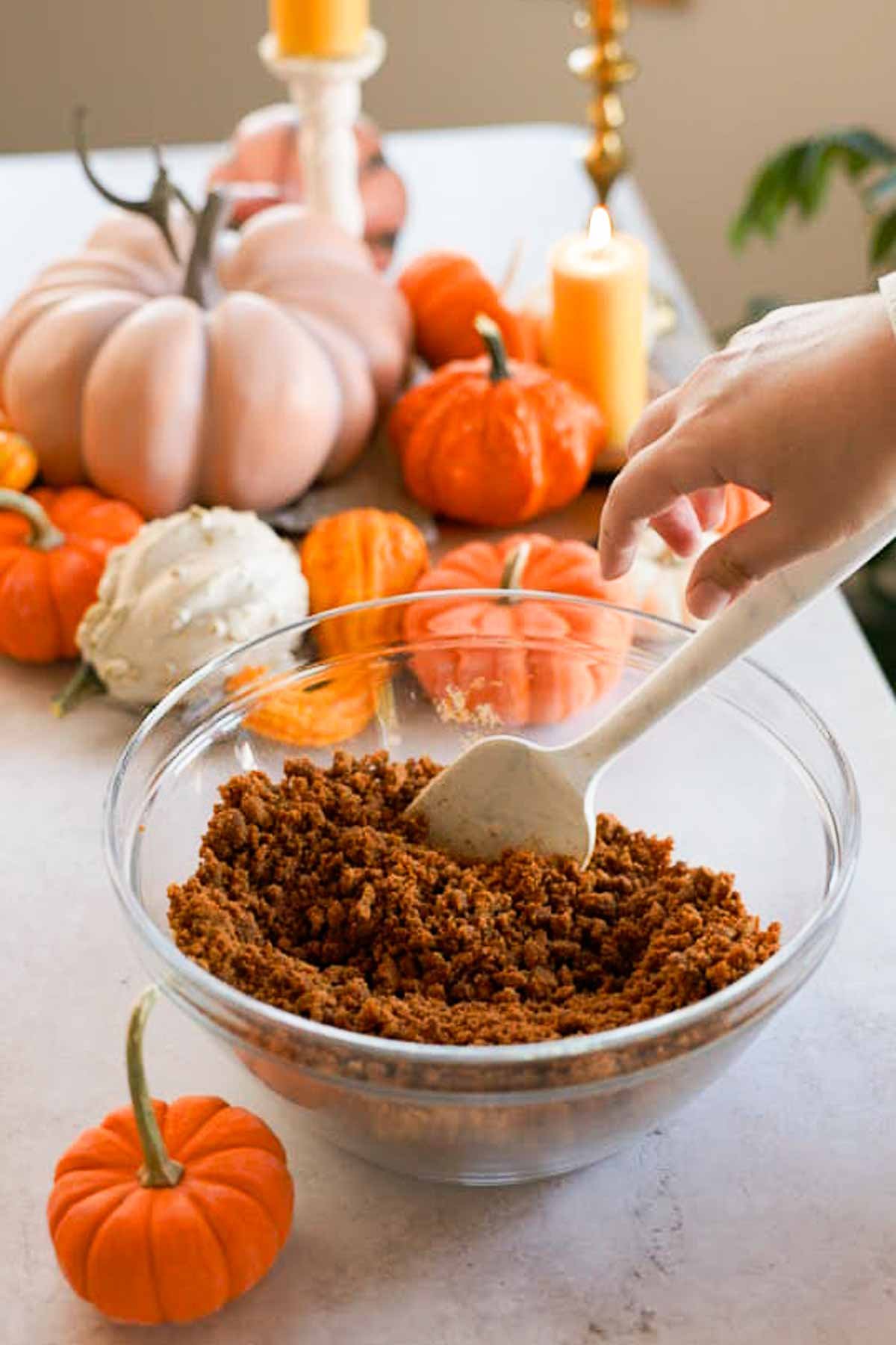 mixing biscoff cheesecake crust in a large glass bowl with a silicone spatula
