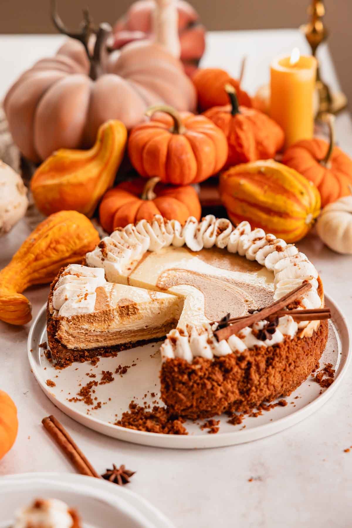 sliced pumpkin pie cheesecake on cake plate with whipped cream