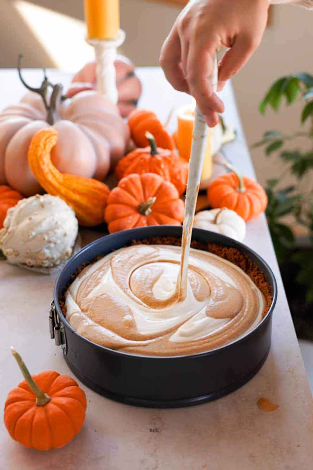 swirling pumpkin pie cheesecake with a spatula