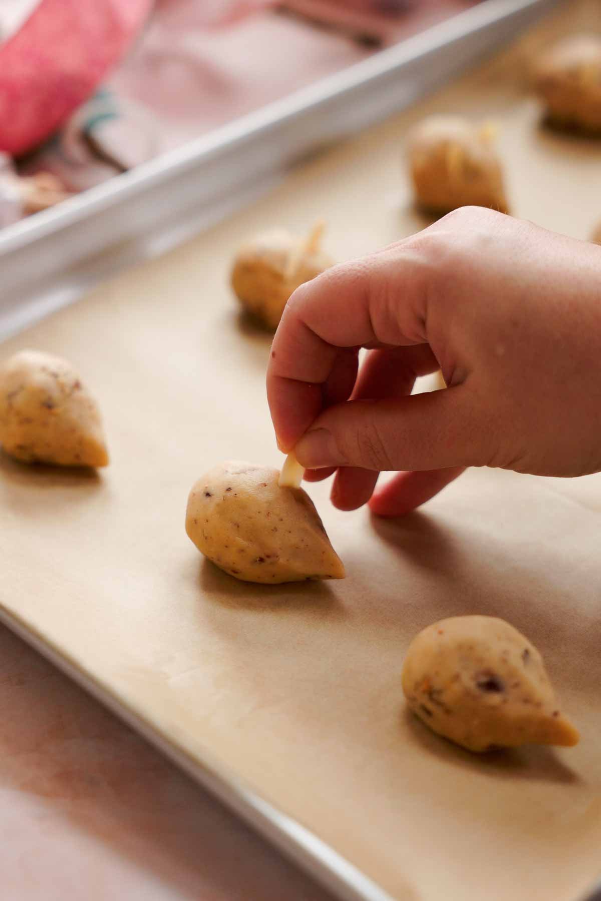 adding sliced almonds as ears onto christmas mice cookies