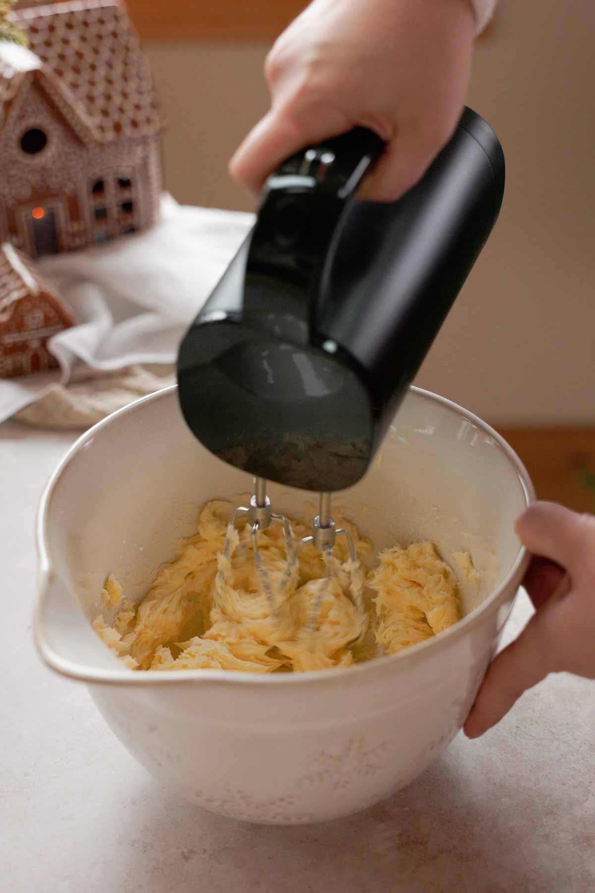 beating butter and powdered sugar in a large bowl with an electric mixer
