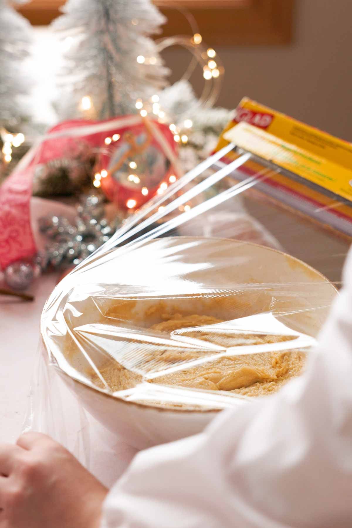 covering bowl of plum cookie dough with plastic wrap