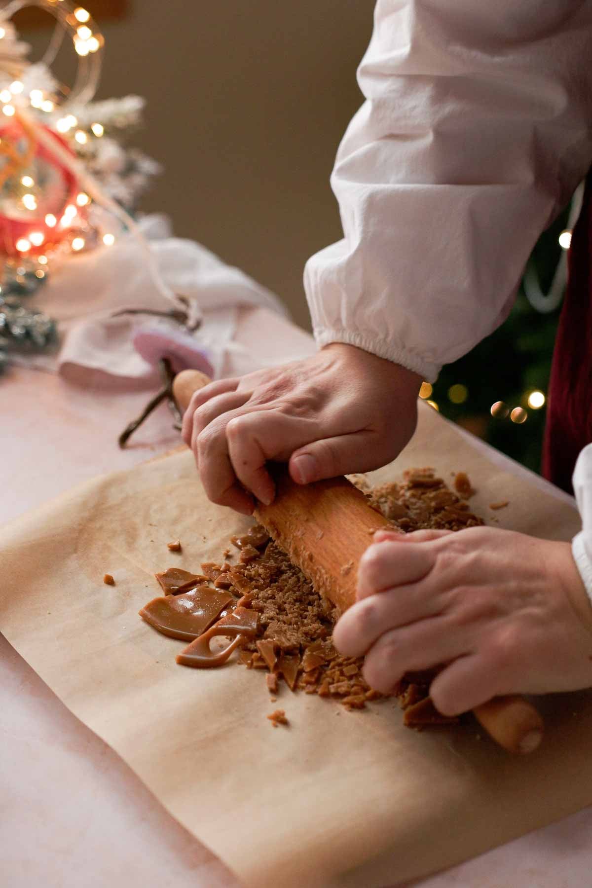 crushing toffee on parchment paper with a rolling pin