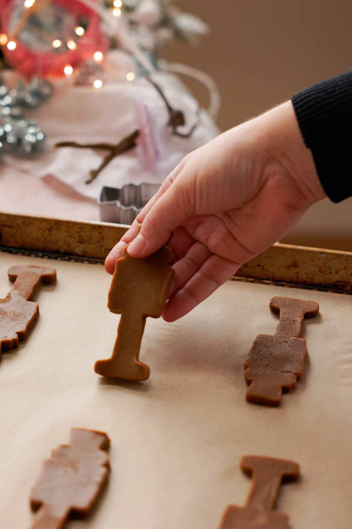 placing cut out gingerbread nutcracker cookies on parchment lined baking sheet