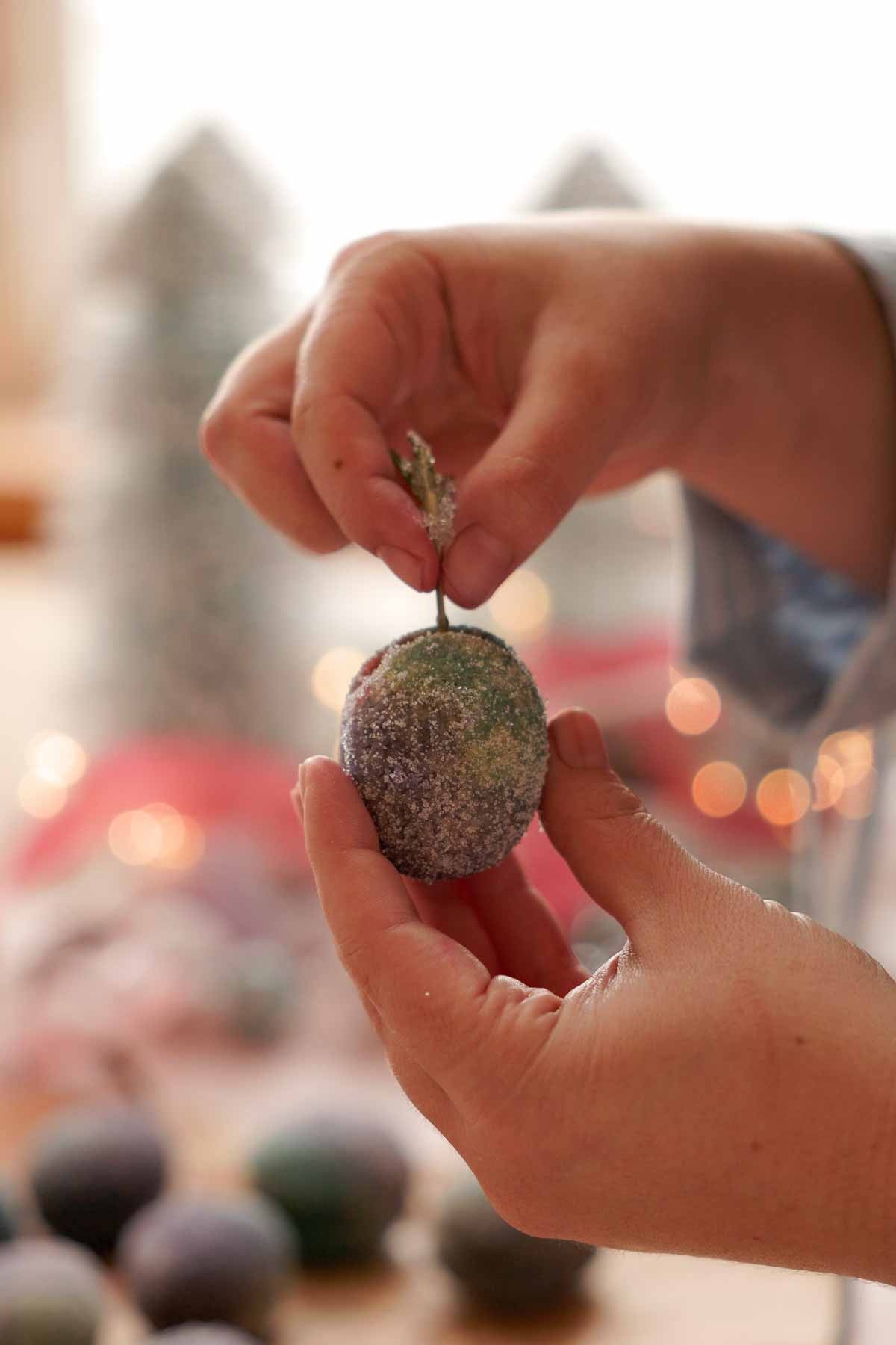 adding sugared rosemary sprig into sugar plum cookie