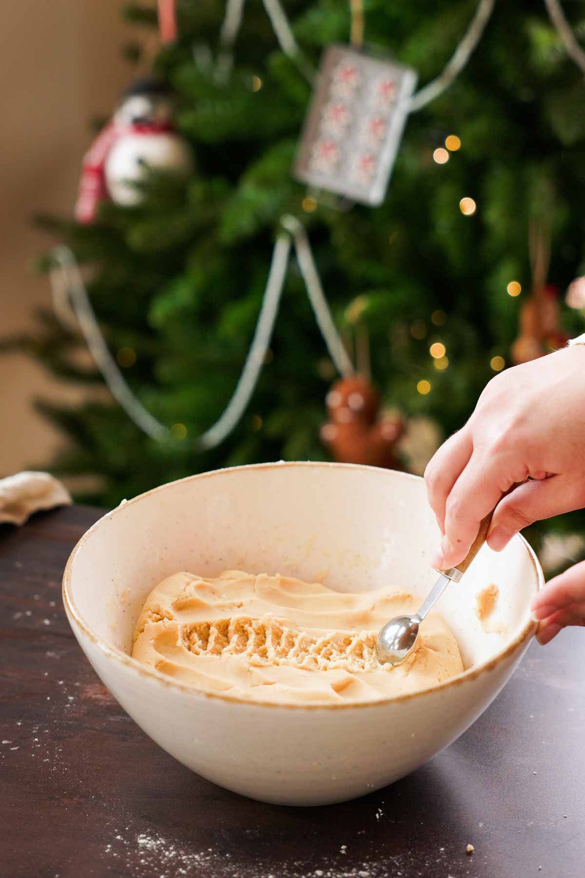 measuring out teaspoons of dough from a large bowl