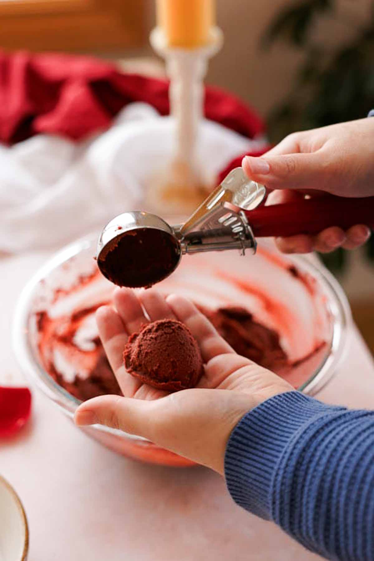 scooping balls of red velvet cookie dough into hand