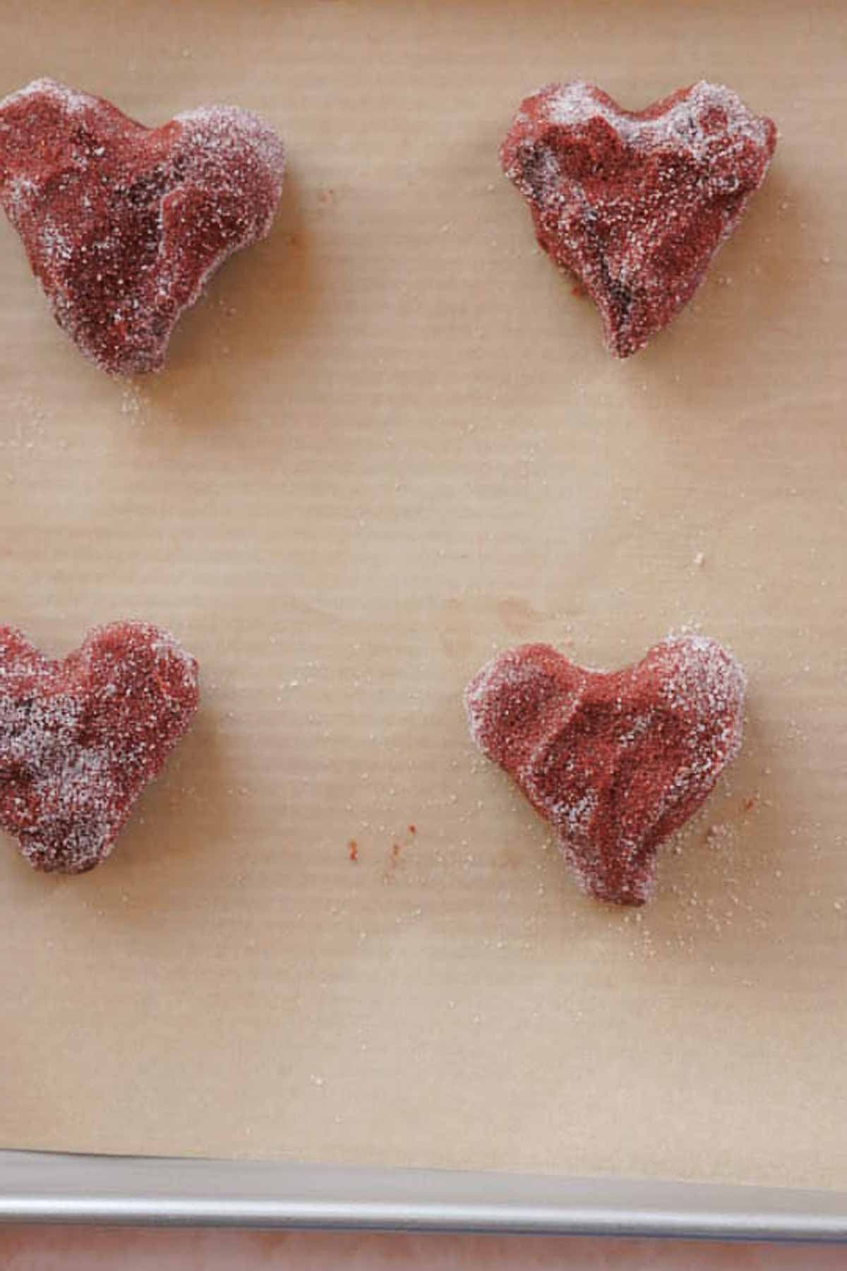 shaped red velvet cookie dough balls on parchment paper