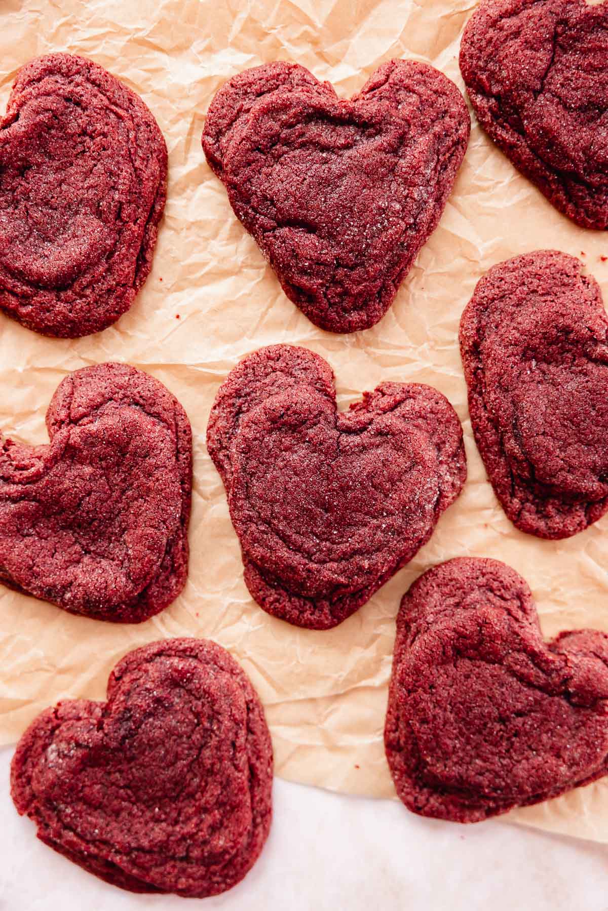 red velvet heart shaped cookies on parchment paper with cream cheese filling